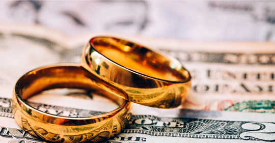 Two wedding rings sitting on top of cash.