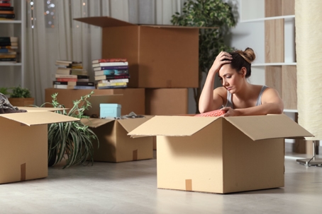 An upset woman packing moving boxes.