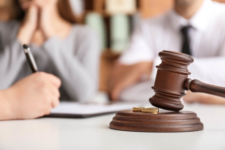 Gavel with two rings and people sitting in the background.