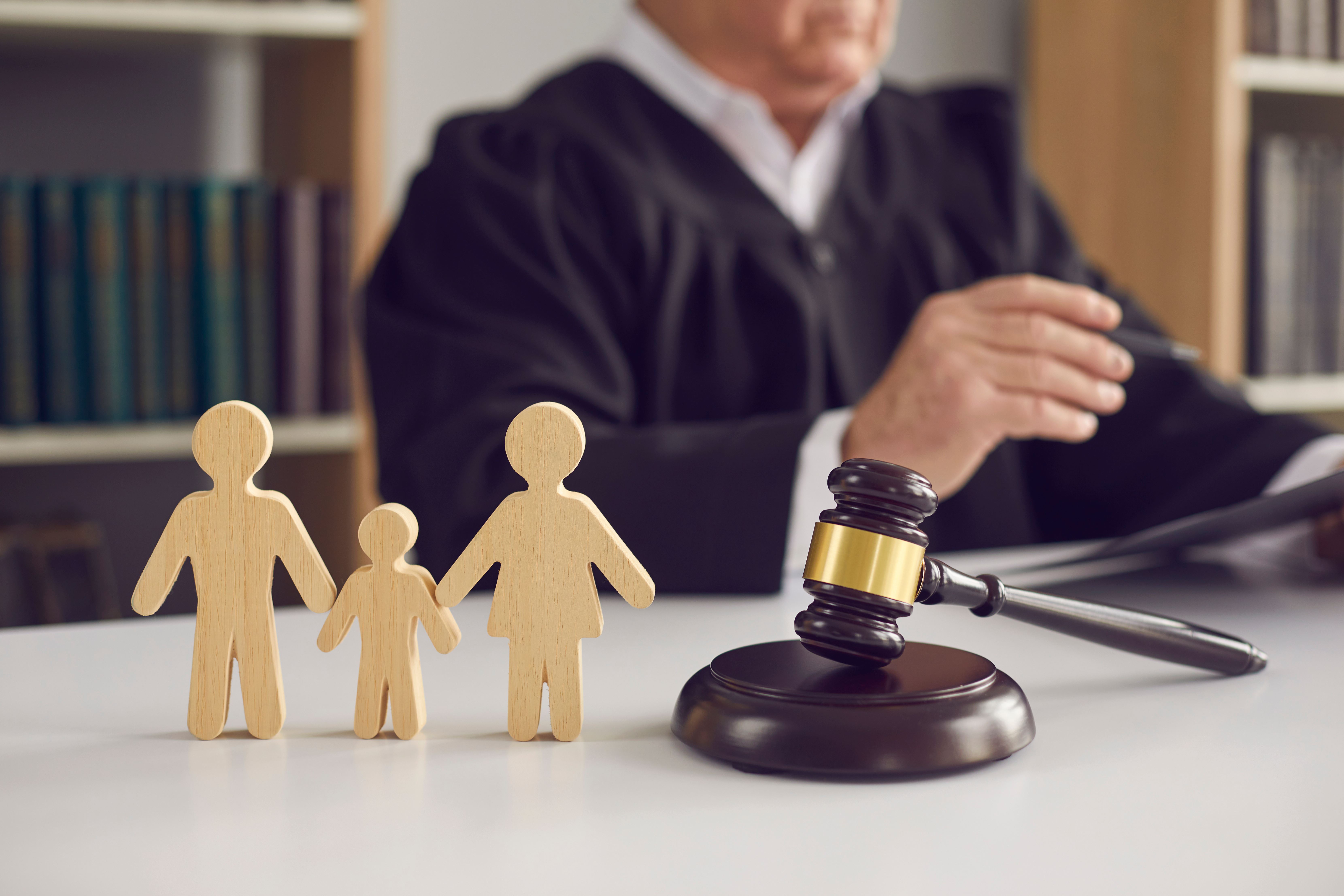 A judge sitting at a table with a gavel and 3 wooden figures.